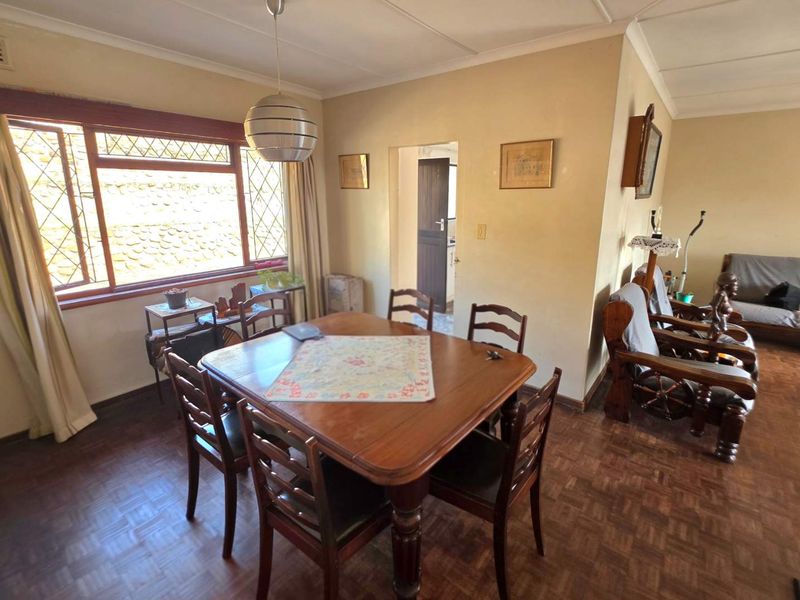 Dining room featuring classic parquet flooring, large windows with security bars, and a coved ceiling, offering a functional space for family meals.
