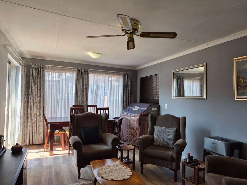A comfortable living room featuring laminate flooring, a ceiling fan, and large sliding glass doors that provide ample natural light.