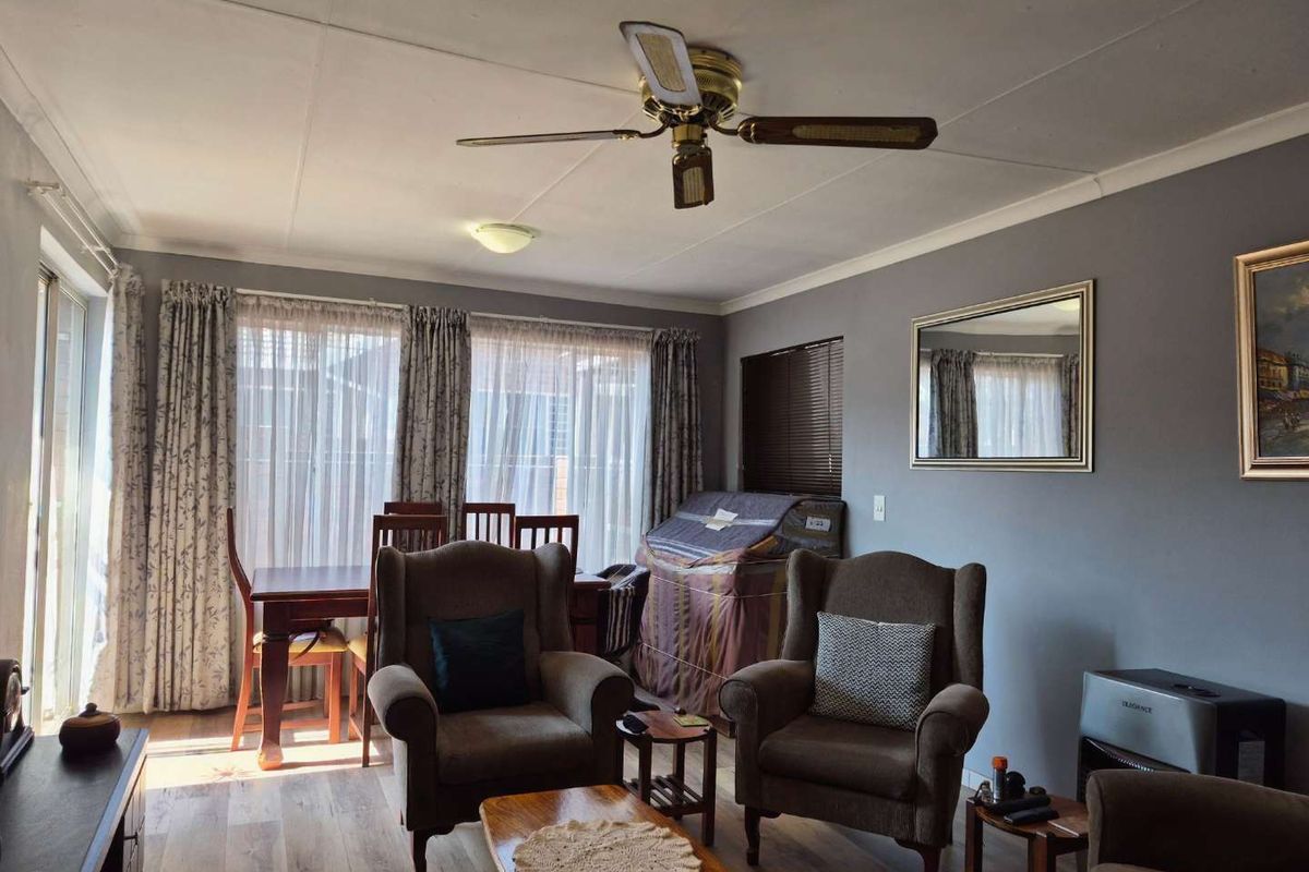 A comfortable living room featuring laminate flooring, a ceiling fan, and large sliding glass doors that provide ample natural light.