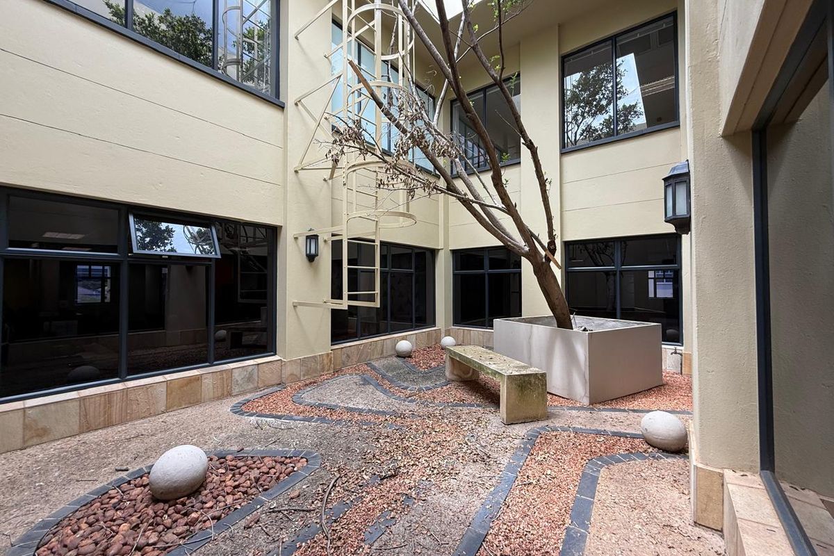 A central office courtyard featuring a spiral staircase, stone-paved ground, and a built-in planter box, providing an outdoor break area for the building.