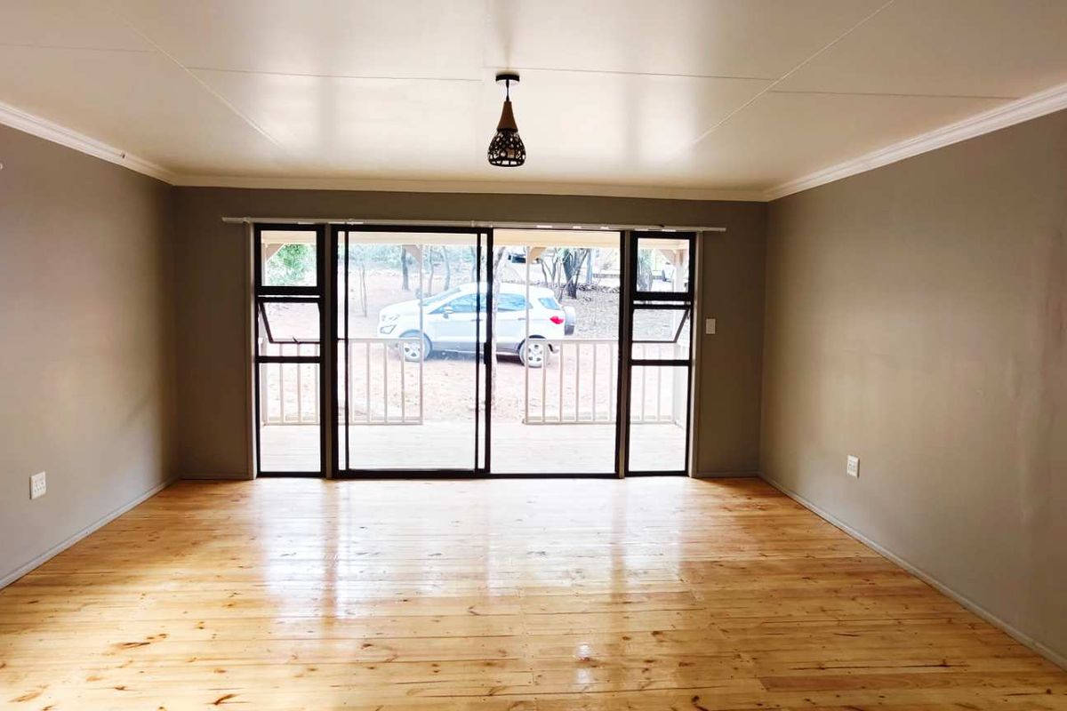 Spacious living area featuring polished timber flooring, neutral wall tones, and large sliding glass doors providing direct access to the outdoor patio.