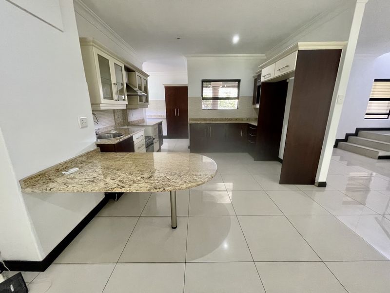 Spacious kitchen featuring granite countertops, ample built-in cabinetry, a breakfast bar, and tiled flooring, offering a clean and functional layout.
