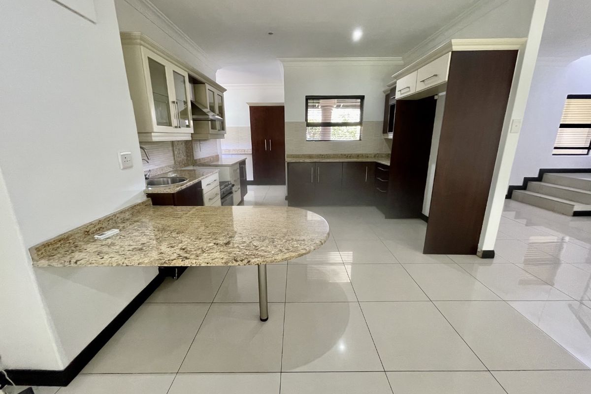 Spacious kitchen featuring granite countertops, ample built-in cabinetry, a breakfast bar, and tiled flooring, offering a clean and functional layout.