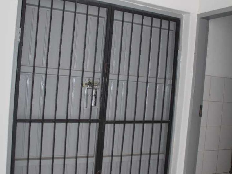 Interior entry area featuring a metal security gate and tiled flooring, requiring maintenance to the floor surface.