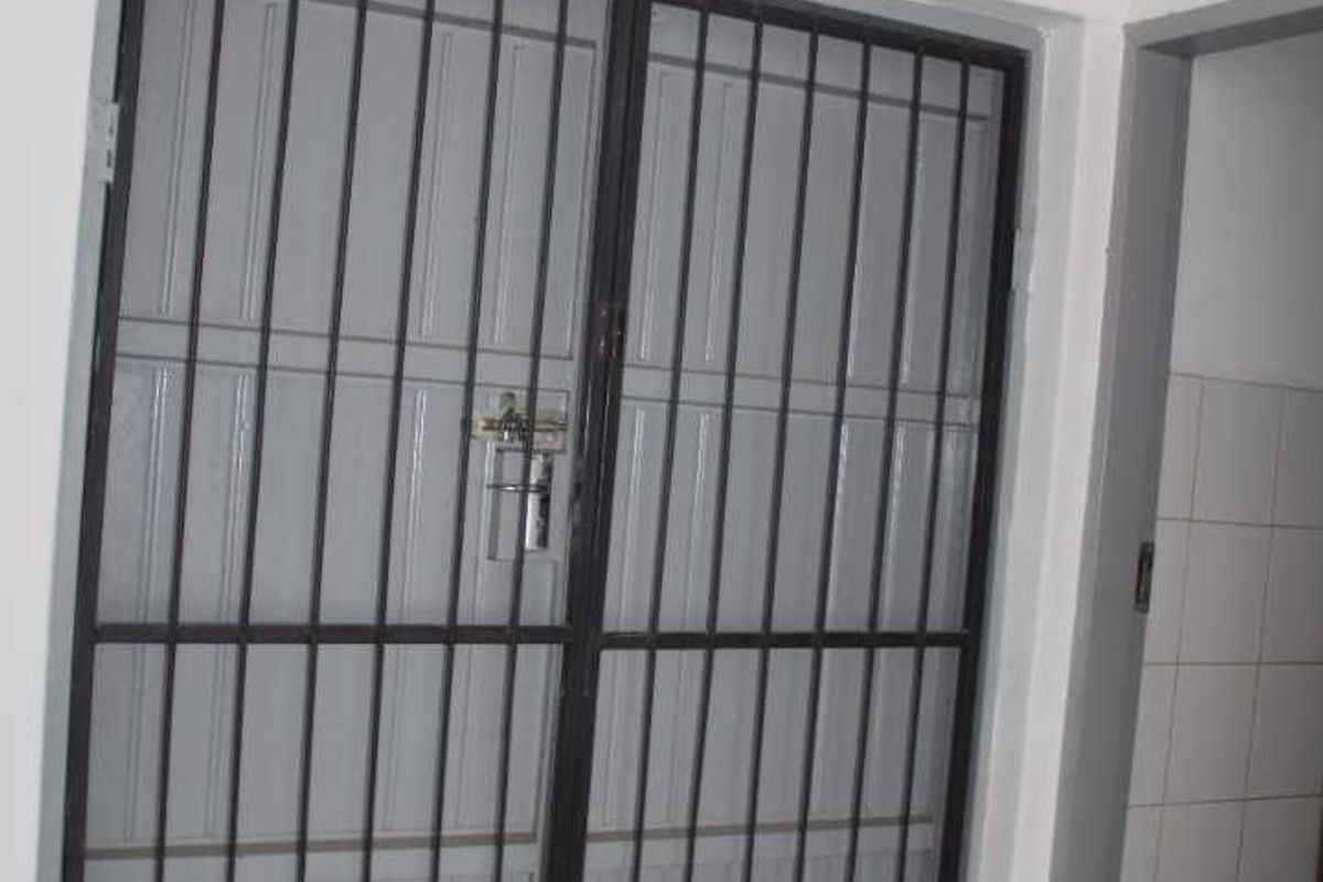 Interior entry area featuring a metal security gate and tiled flooring, requiring maintenance to the floor surface.