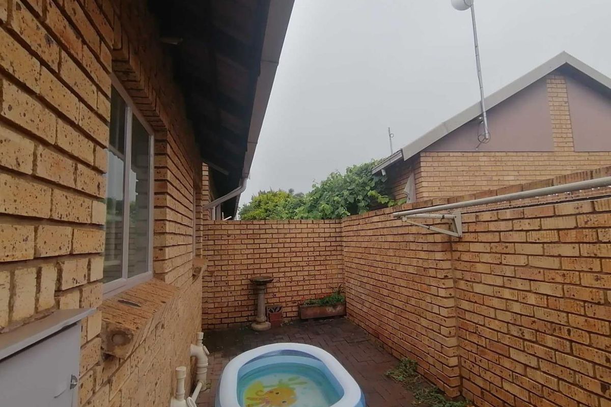 A side courtyard area featuring face-brick walls, paved flooring, and a wall-mounted clothes drying rack.