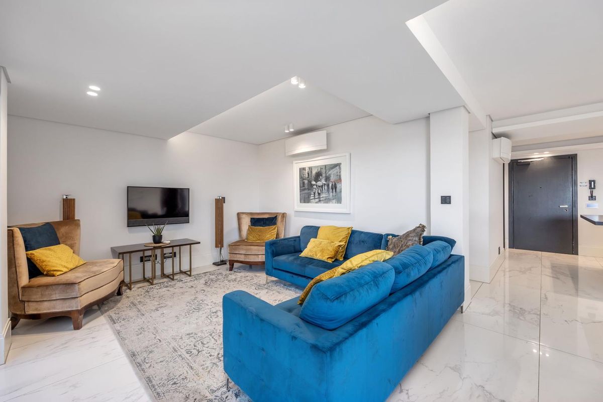 A modern, well-maintained living room featuring polished marble-look flooring, recessed ceiling lighting, and a wall-mounted air conditioning unit.