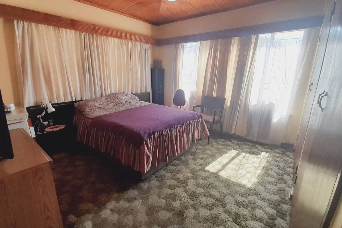 A bedroom featuring a timber-clad vaulted ceiling, built-in wardrobe storage, and large windows allowing natural light.