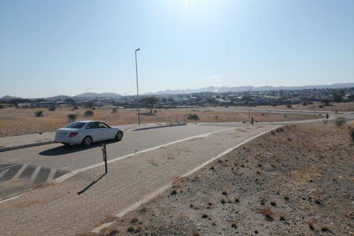 An elevated view of the industrial property surroundings, featuring paved access roads, street lighting, and expansive open land with distant mountain views.