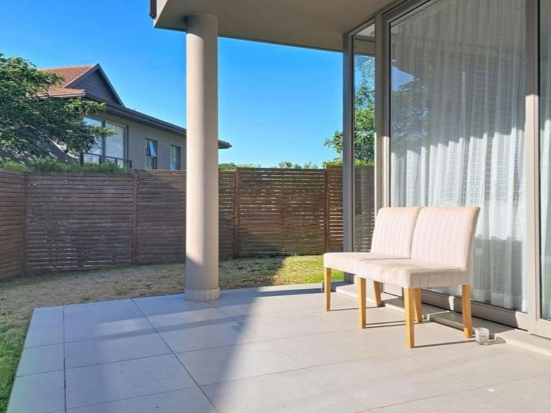 A covered patio area featuring tiled flooring, a structural support column, and large sliding glass doors leading into the interior living space.