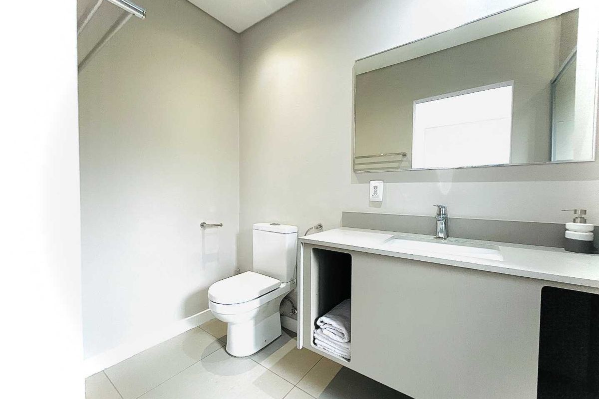 A modern, clean bathroom featuring a wall-mounted vanity with integrated basin, large mirror, and a contemporary toilet.