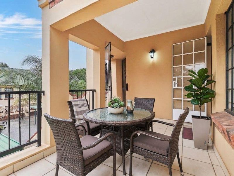 A covered balcony featuring tiled flooring, wrought iron railings, and a wall-mounted light fixture, providing a pleasant outdoor space.