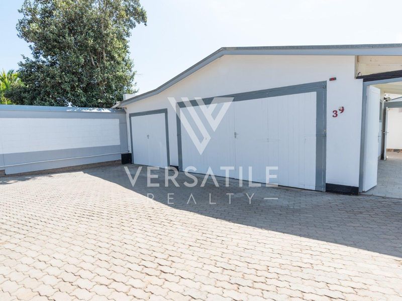 Exterior view of a double garage with a paved driveway and surrounding boundary wall.