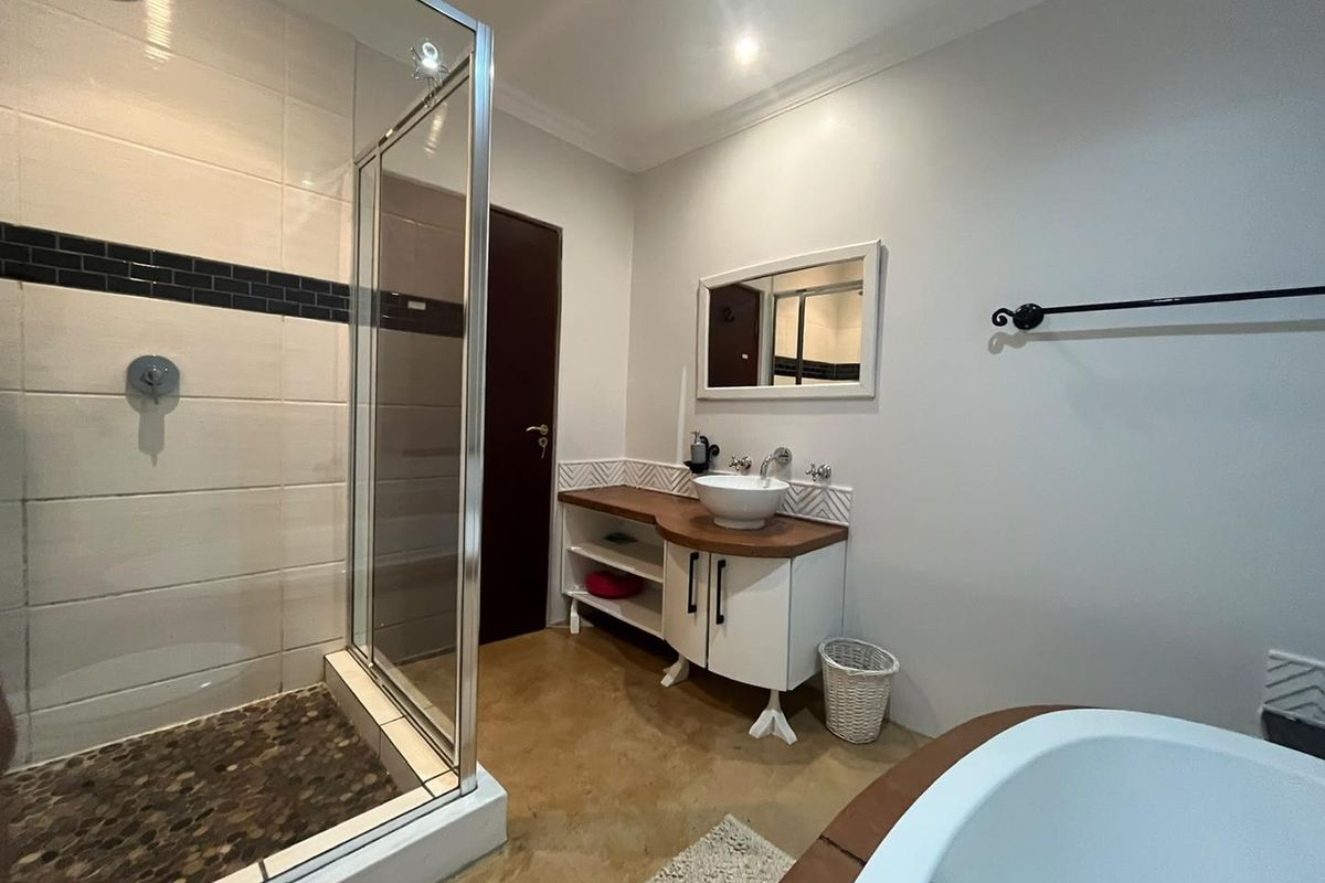 Modern bathroom featuring a glass-enclosed shower with pebble flooring, a vessel sink vanity, and a freestanding bathtub.
