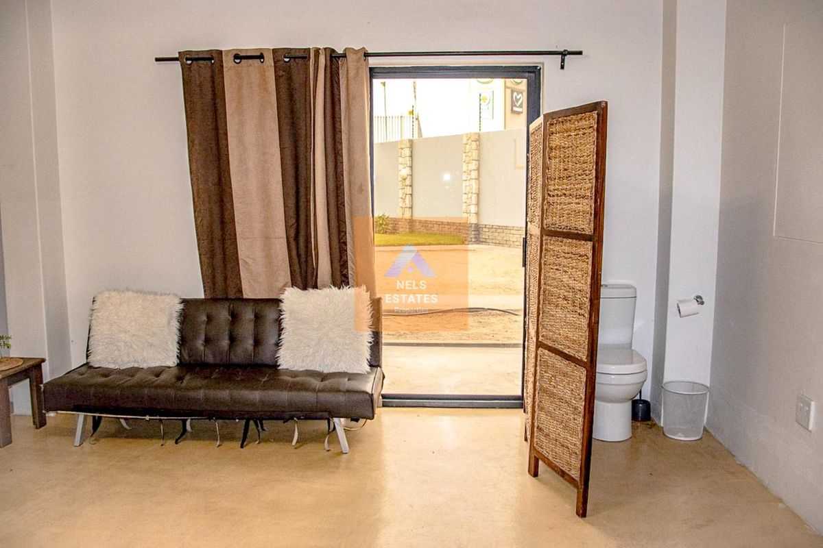 A functional bathroom space featuring a toilet, polished concrete flooring, and a sliding glass door providing direct access to the exterior.