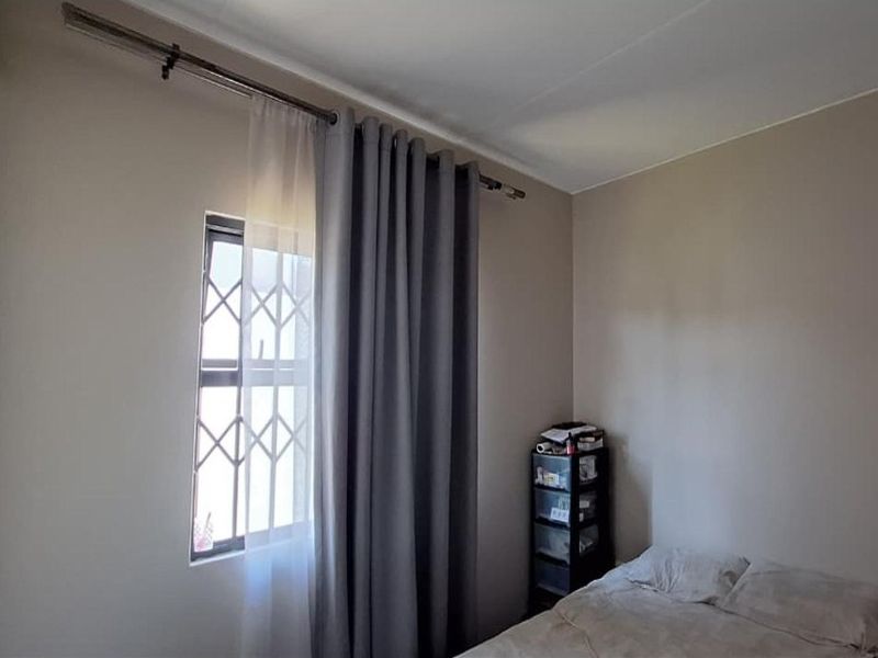 A bedroom featuring a window with a fitted security gate and curtain rod, providing natural light and basic security.