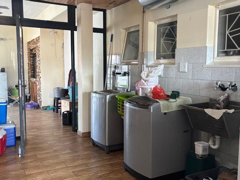 Functional laundry area featuring tiled flooring, a utility sink, and wall-mounted water heater, with direct access to adjacent living spaces.