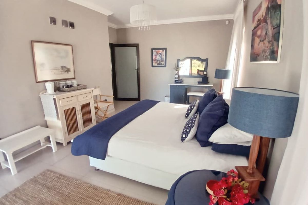 A well-maintained bedroom featuring neutral wall tones, tiled flooring, and a glass-panelled door leading to an adjoining space.