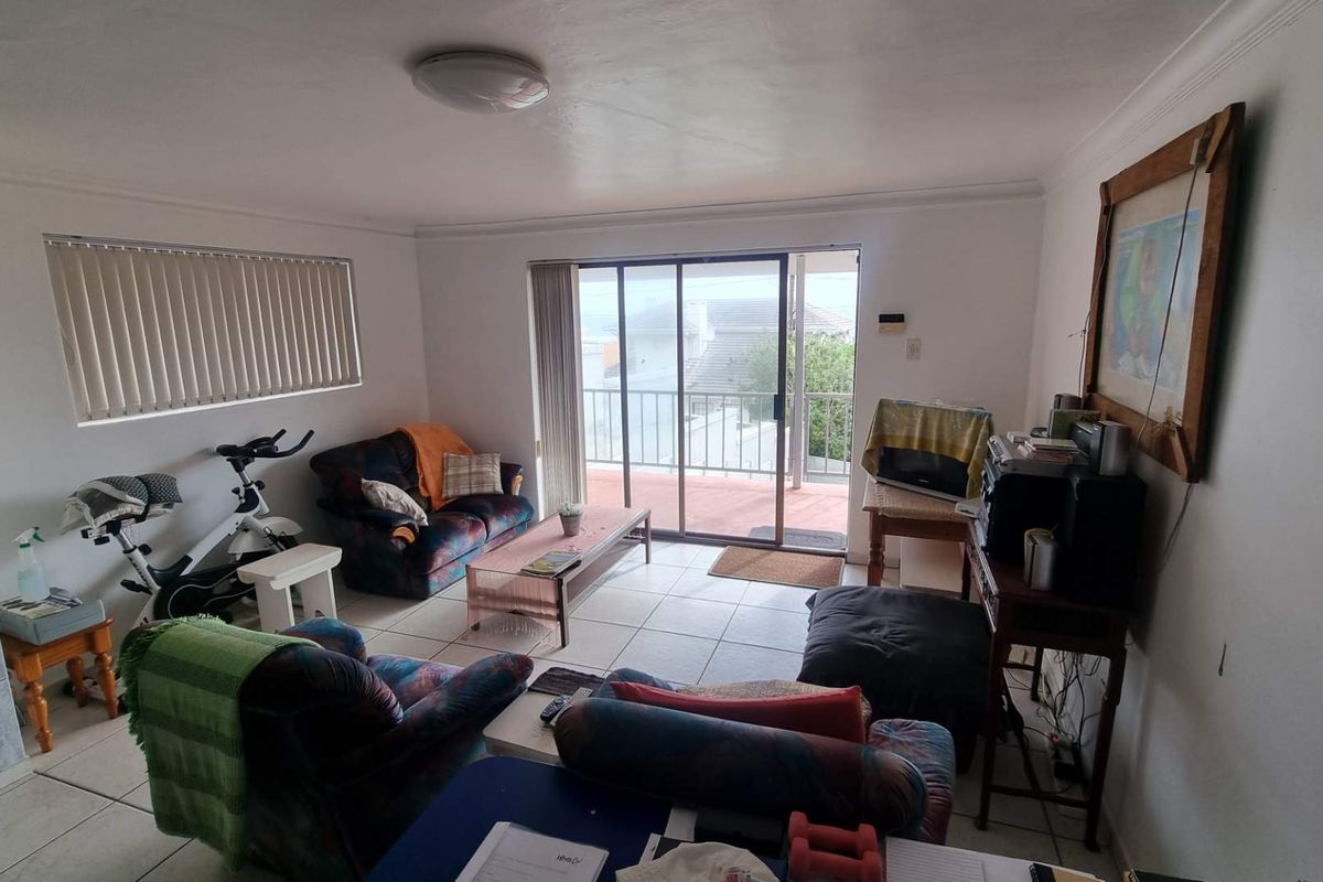 A living room featuring tiled flooring and sliding glass doors that open onto an outdoor balcony area.