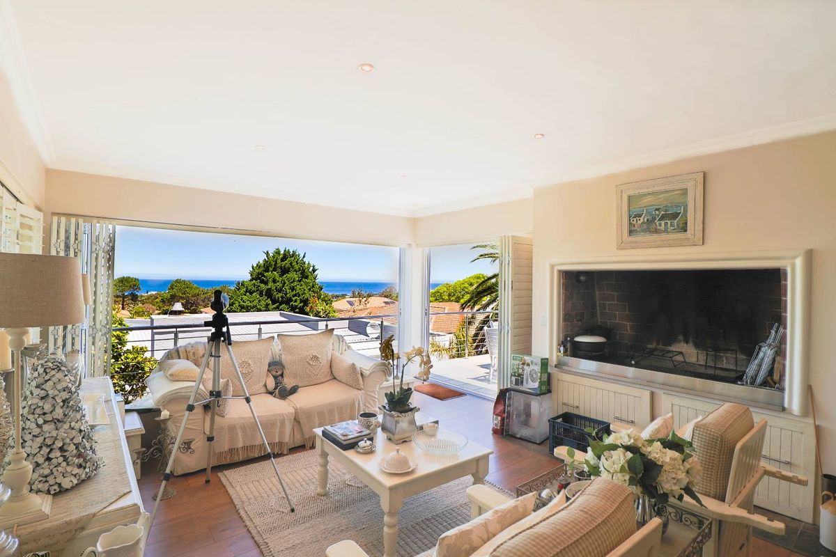 Spacious living room featuring a built-in fireplace, laminate flooring, and large stacking glass doors that open to a balcony with scenic ocean views.