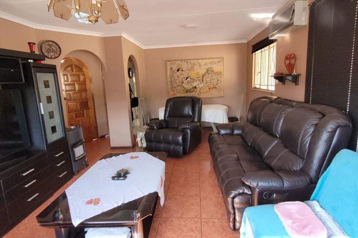A living room featuring tiled flooring, coved ceilings, and an archway leading to other areas of the home.