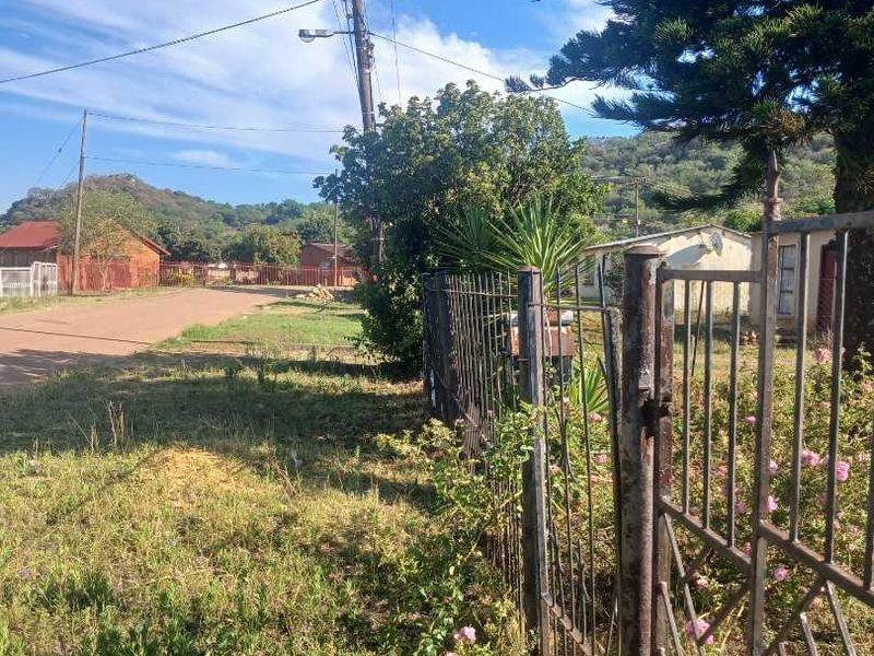 Street view showing the property boundary with a metal fence, gate, and utility infrastructure in a residential neighborhood setting.