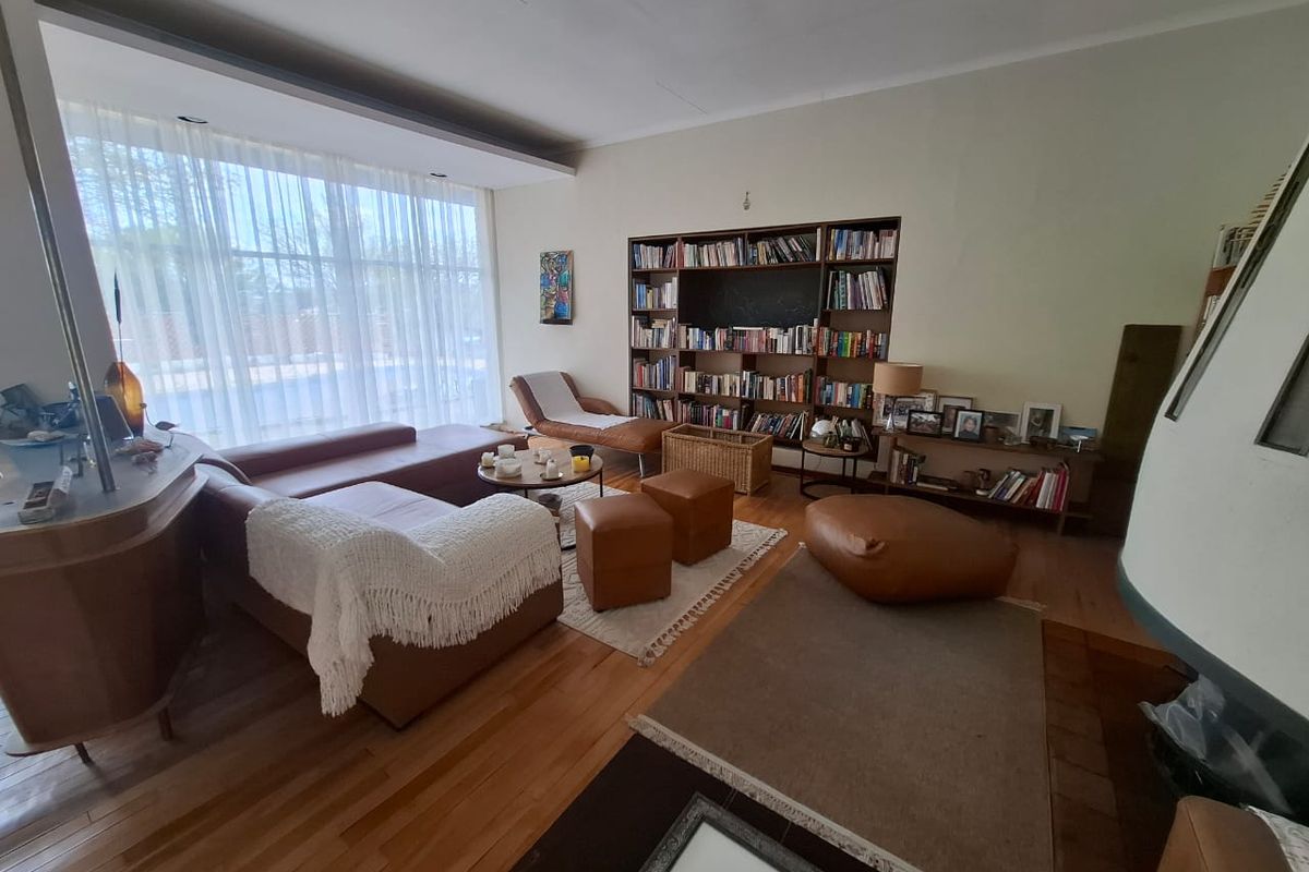 Spacious living room featuring warm hardwood flooring, a large floor-to-ceiling window, and a custom built-in bookshelf, creating a comfortable and inviting atmosphere.