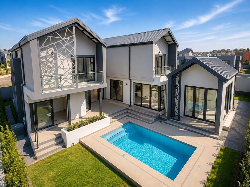 Modern double-story residence featuring a swimming pool, concrete patio, decorative metal screening, and expansive glass sliding doors opening to the rear garden.