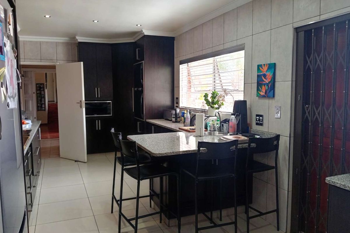A functional kitchen featuring dark cabinetry, granite countertops, a breakfast bar, and tiled flooring, offering a practical layout for daily meal preparation.