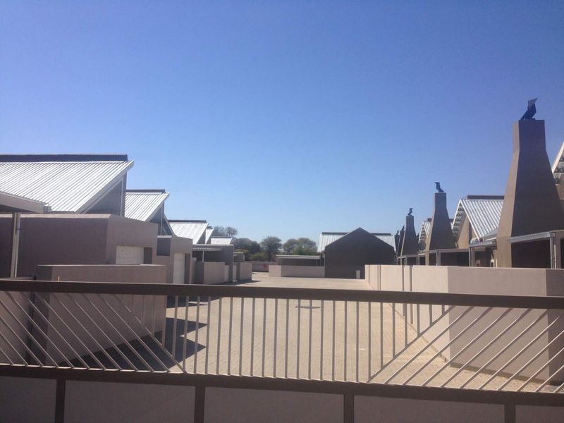 View of the townhouse complex driveway and exterior facades featuring modern architectural design with metal roofing and prominent chimneys.
