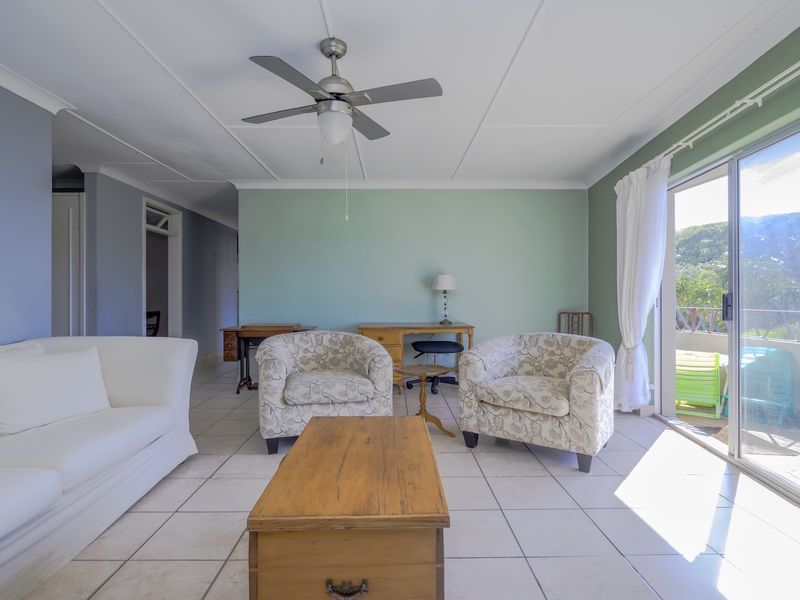 Spacious living room featuring tiled flooring, a ceiling fan, and large sliding glass doors providing access to an outdoor balcony area.
