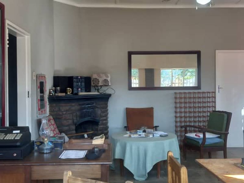 A living area featuring a stone fireplace and wall-mounted air conditioning unit, offering a functional space with potential for modernization.