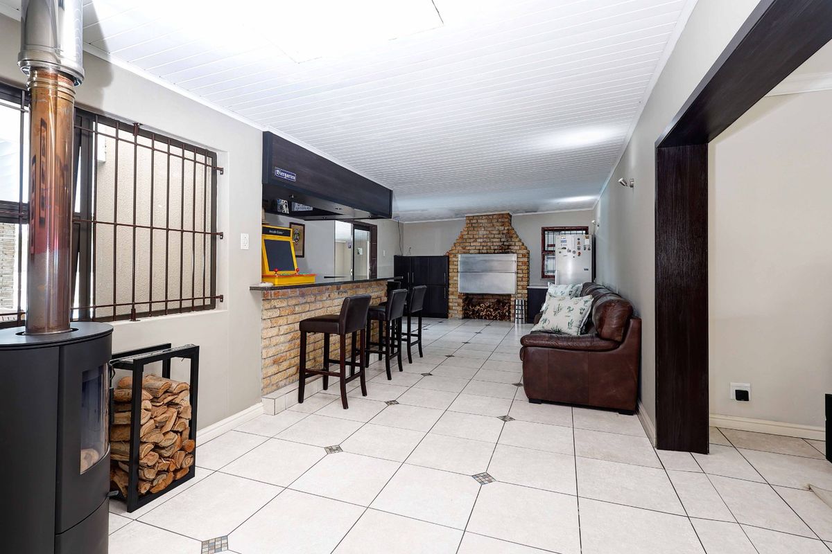Spacious living area featuring a built-in bar, brick fireplace, wood-burning stove, and tiled flooring, offering a functional entertainment space.