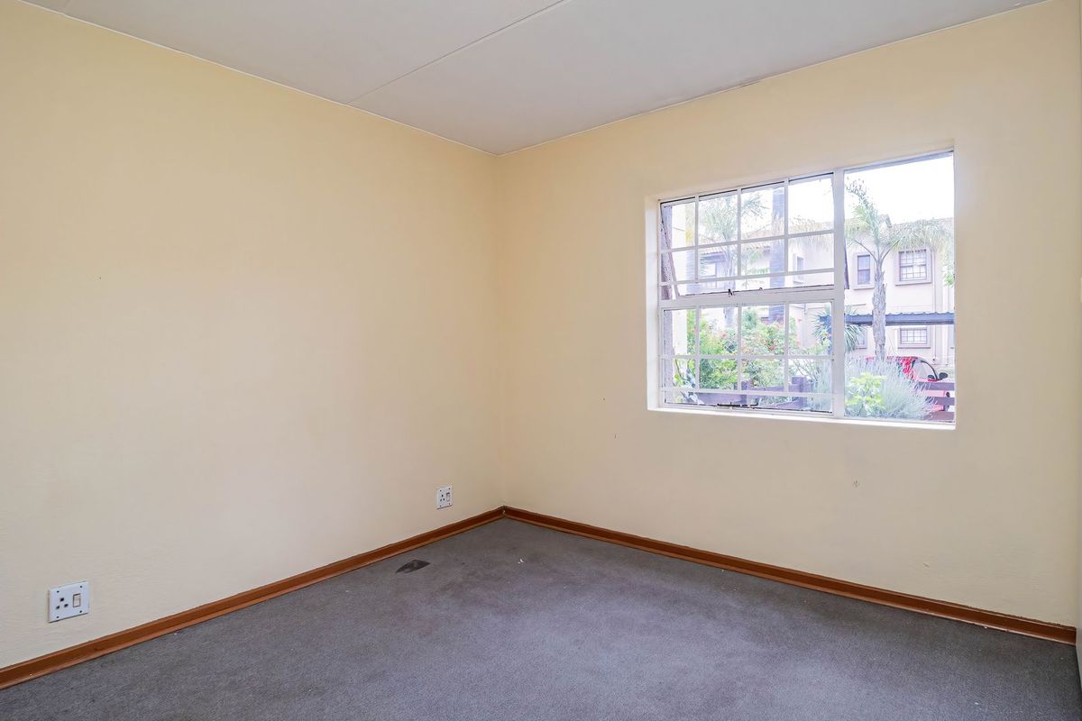 An empty bedroom featuring neutral walls, carpeted flooring, and a built-in cupboard, offering a blank canvas for personalization.