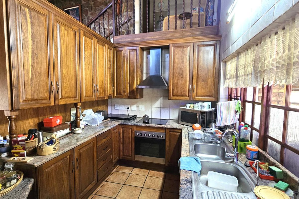 A functional kitchen featuring traditional timber cabinetry, granite countertops, a built-in oven with extractor fan, and a double stainless steel sink.