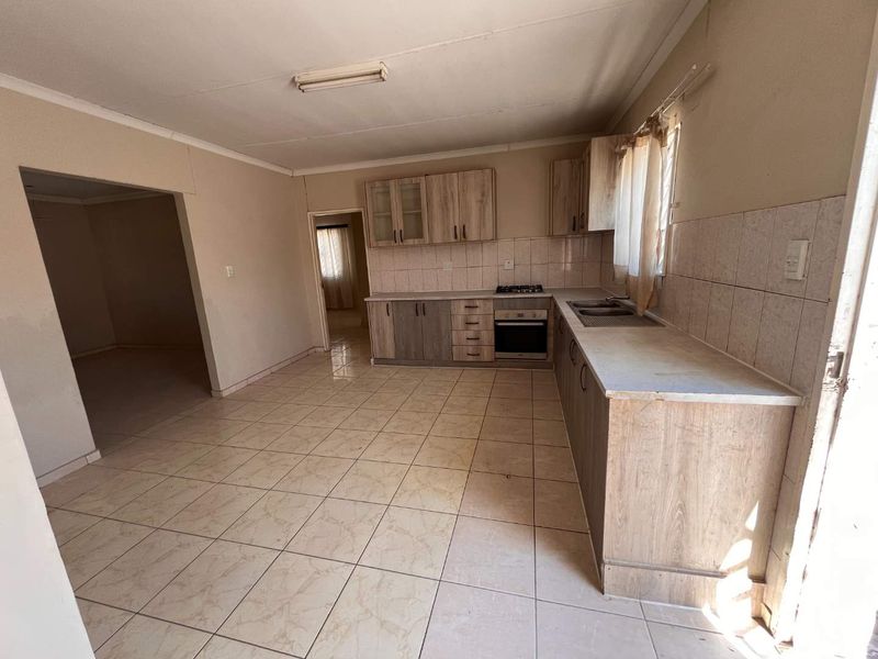 A functional kitchen featuring built-in cabinetry, a gas hob, an integrated oven, and tiled flooring, offering a blank canvas for potential updates.