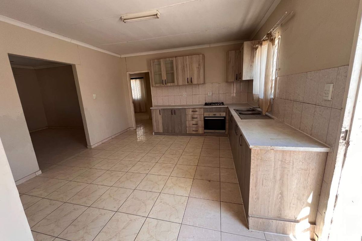 A functional kitchen featuring built-in cabinetry, a gas hob, an integrated oven, and tiled flooring, offering a blank canvas for potential updates.