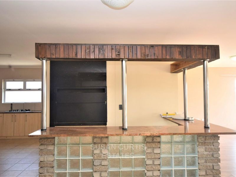 A spacious kitchen featuring a unique glass block breakfast bar with granite countertop, timber bulkhead, and integrated cooking appliances.