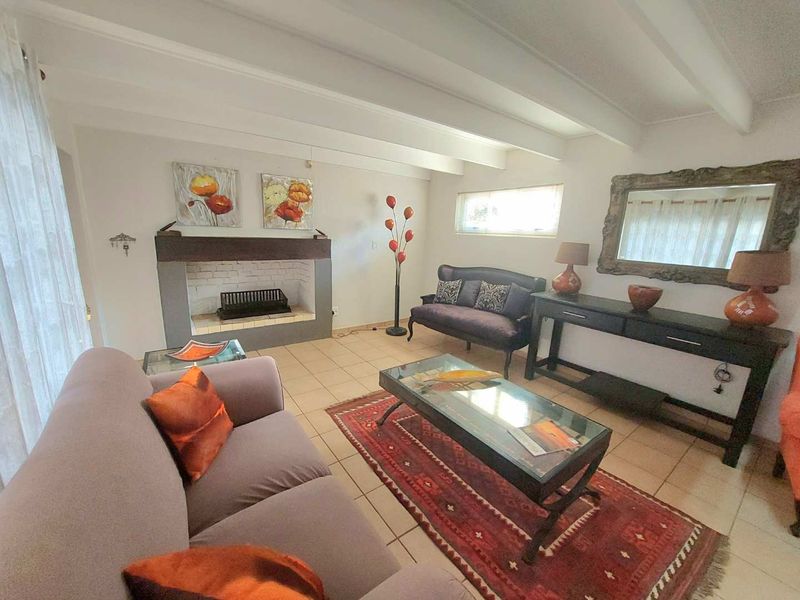 A cozy living room featuring a built-in fireplace, exposed ceiling beams, and neutral tiled flooring, offering a comfortable and inviting atmosphere.