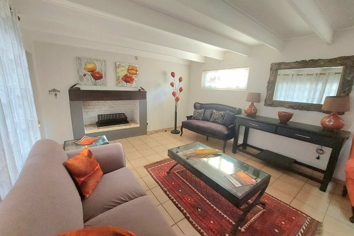 A cozy living room featuring a built-in fireplace, exposed ceiling beams, and neutral tiled flooring, offering a comfortable and inviting atmosphere.