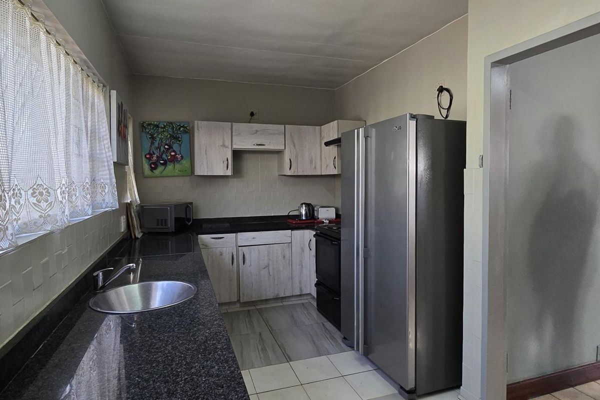 A functional kitchen featuring granite countertops, built-in cabinetry, and tiled flooring, offering a practical workspace with a clean, neutral aesthetic.