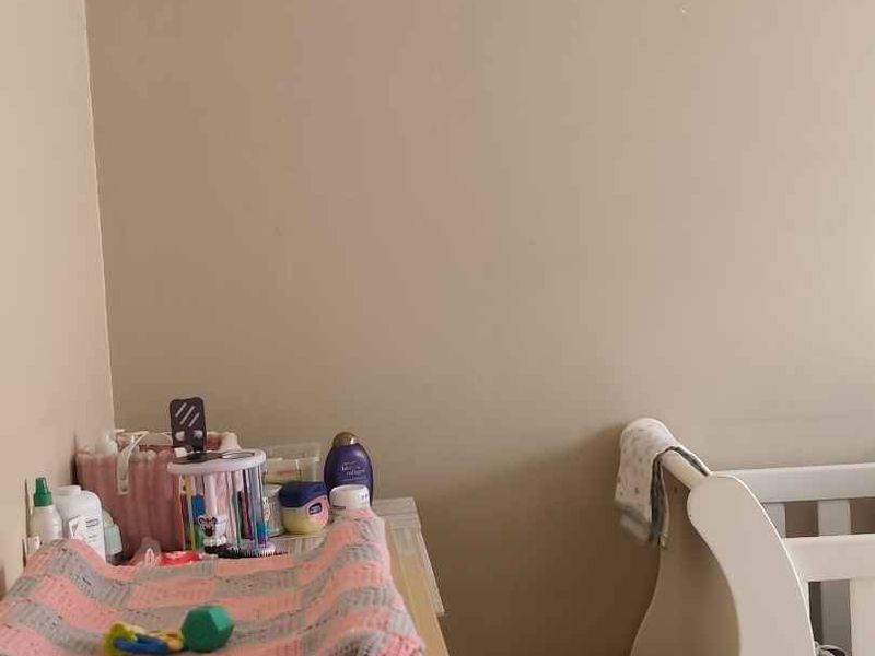 A corner view of a bedroom featuring neutral wall paint.