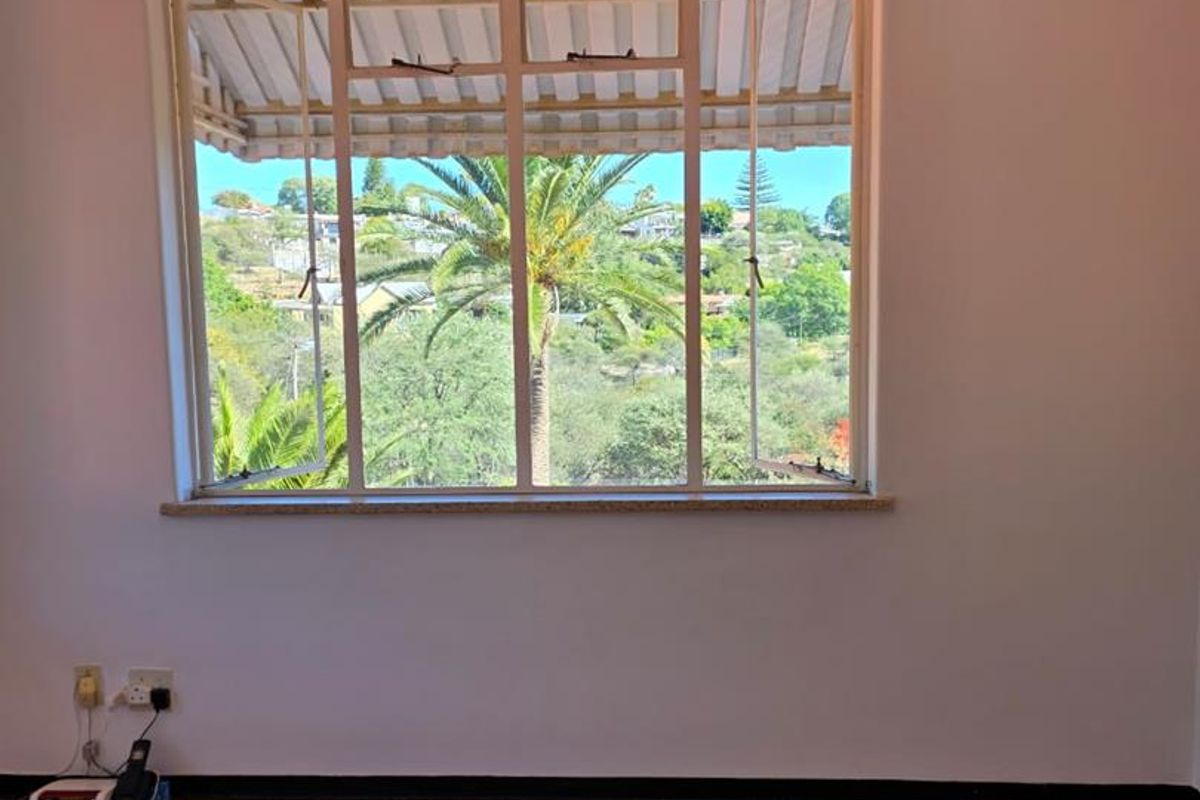 A bright bedroom featuring original parquet flooring, a large window with scenic views, and a decorative pendant light fixture.