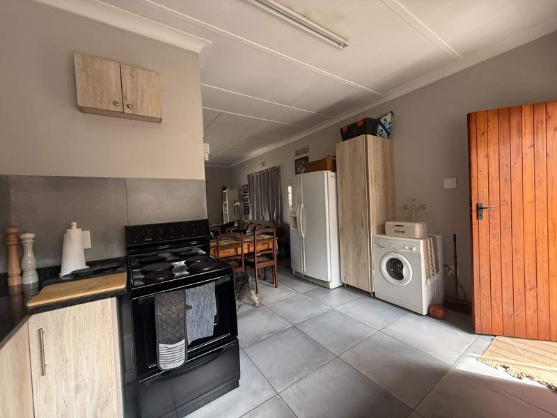 Open-plan kitchen and living area featuring tiled flooring, modern cabinetry, and a freestanding stove, providing a functional and connected living space.
