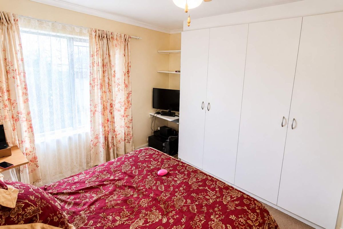A bedroom featuring built-in white wardrobes and a window with natural light.