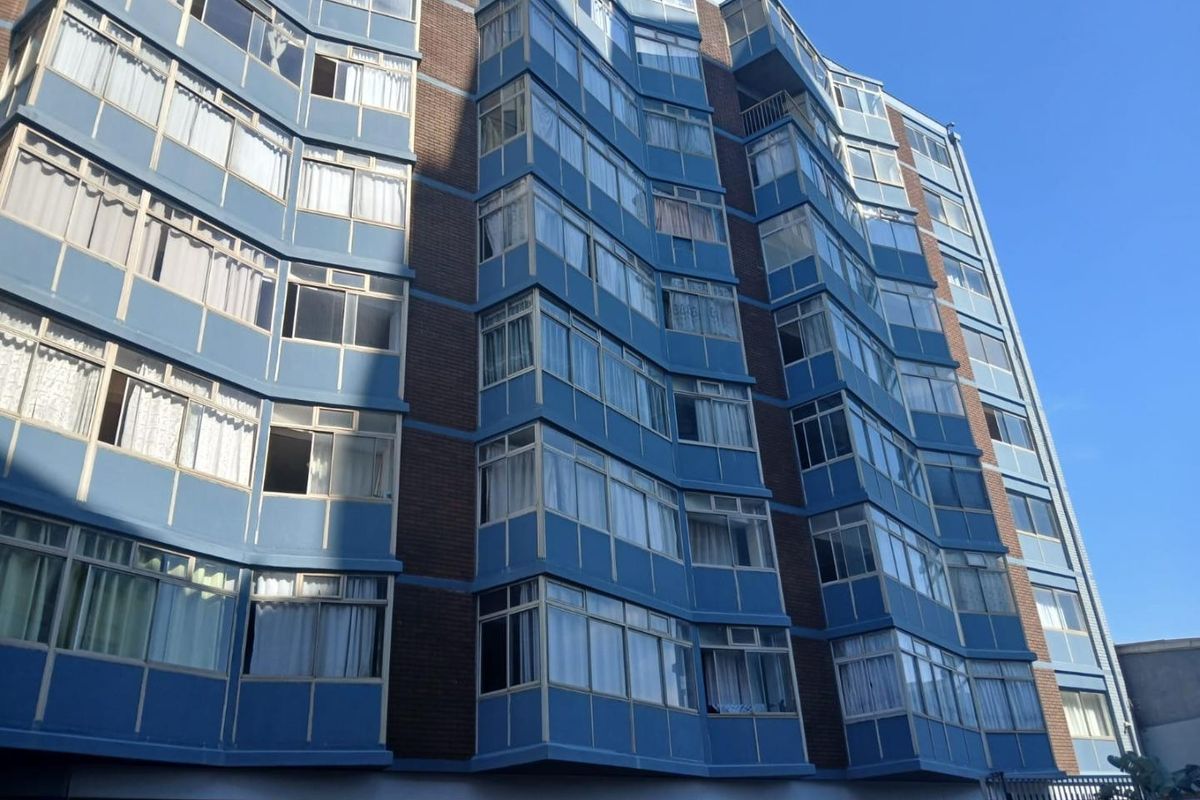 Exterior view of a multi-story apartment building featuring a brick facade and multiple levels of enclosed balconies.