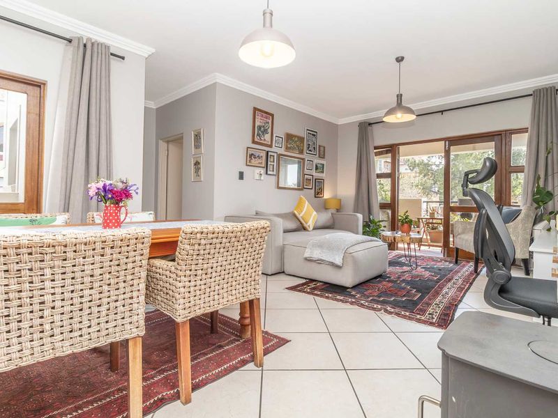 Spacious open-plan living and dining area featuring tiled floors, pendant lighting, and large sliding glass doors leading to an outdoor patio.