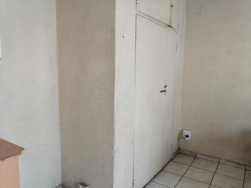 A vacant bedroom space featuring tiled flooring and a built-in cupboard, requiring cosmetic updates to improve the overall condition and appeal.