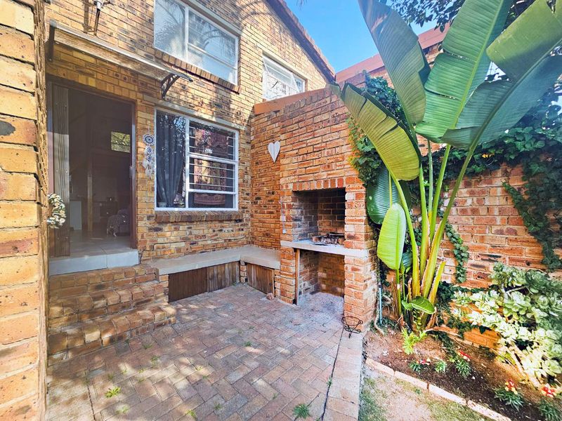 A private rear courtyard featuring a built-in brick braai, paved flooring, and a built-in bench, providing a functional outdoor entertainment space.