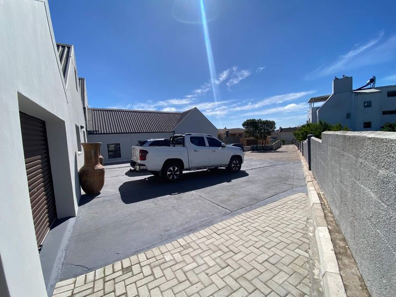 Front exterior view of the property featuring a paved driveway, concrete boundary wall, and garage access.